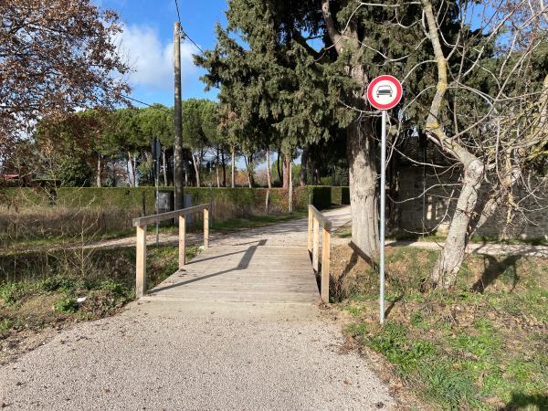 Small wooden bridge, lacking cane-beater and pedo-tactile markers. A sign prohibits access by motor vehicle.